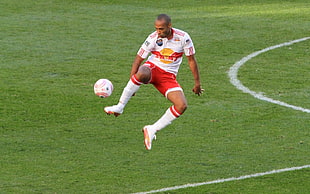 man wearing white and red jersey playing soccer on field